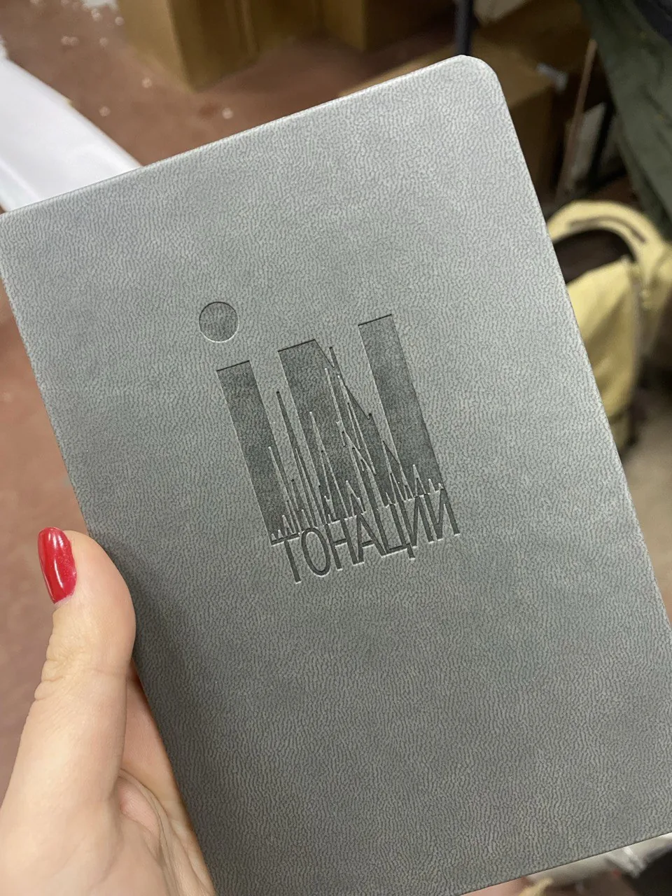 Блинтовое тиснение логотипа на серой обложке блокнота