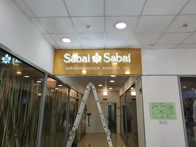 Вывеска SPA-салона в ТЦ: белые объёмные буквы на золотой панели над входом