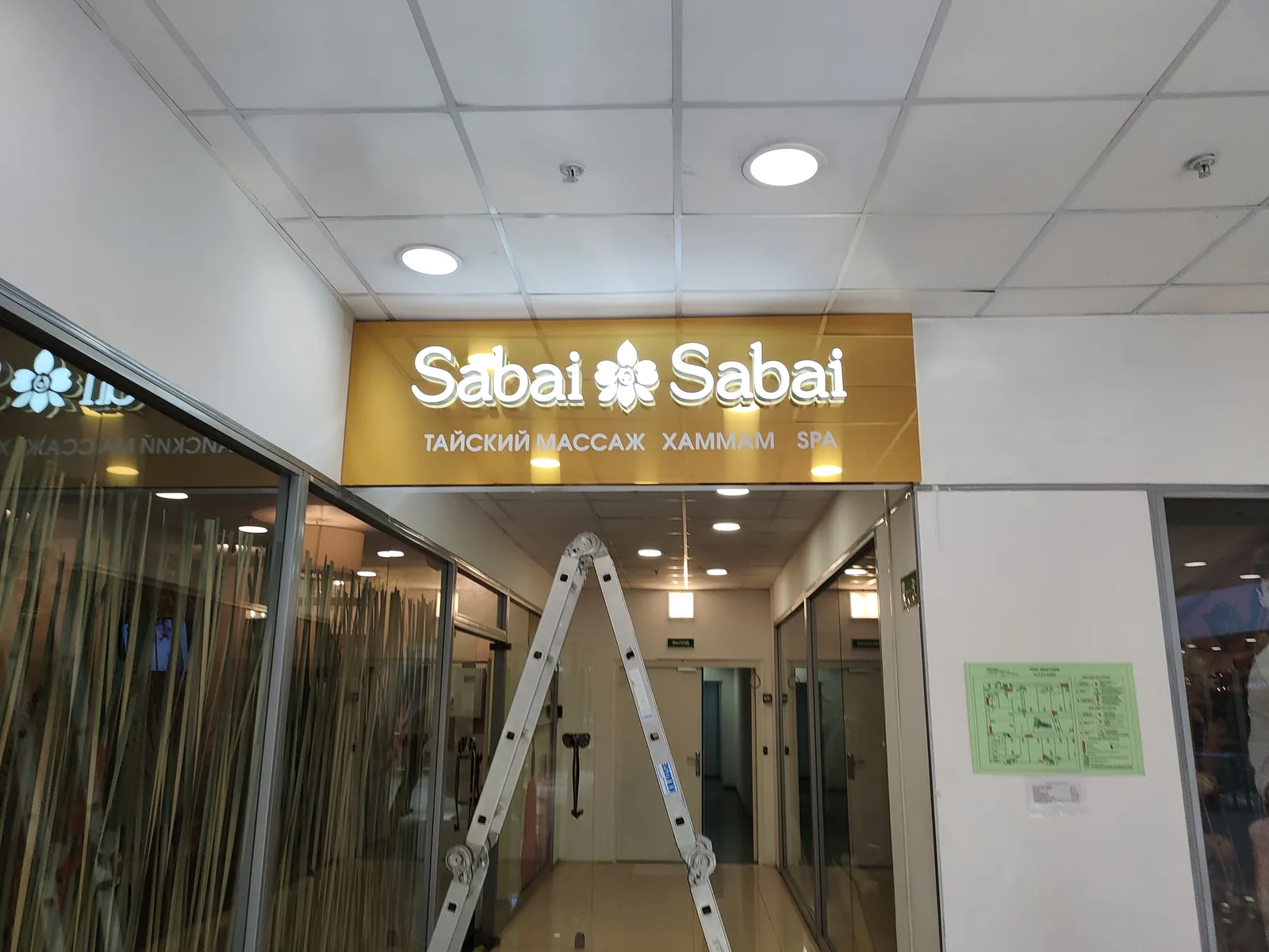 Вывеска SPA-салона в ТЦ: белые объёмные буквы на золотой панели над входом
